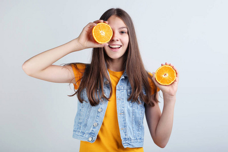 年轻女孩举行橙色果子在灰色背景
