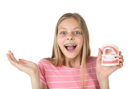 年轻的微笑的女孩与牙套牙模型隔绝在白色背景上