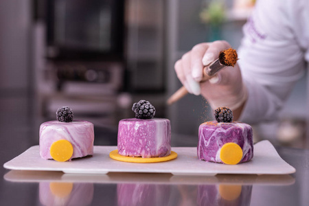 蛋糕大师厨师装饰她的蛋糕与肉桂举行面包店刷子照片