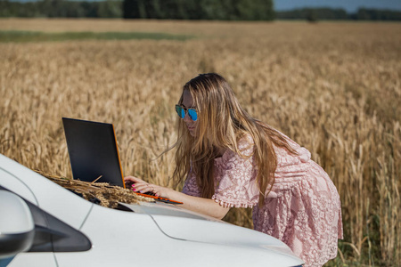 女孩工作在一个笔记本电脑附近的麦田
