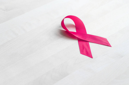 乳癌意识的概念。木桌上的粉红色丝带