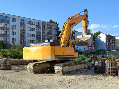 黄色挖掘机在工地附近的道路建设工作, 在住宅楼, 夏季天, 后视图