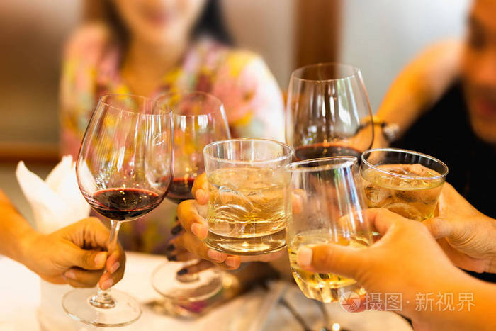 一组朋友在家庭晚宴上举杯庆祝红酒和威士忌杯