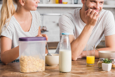 夫妇在厨房吃早饭, 玉米片和桌子上的牛奶瓶