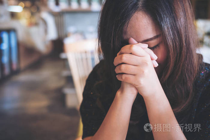 一个亚洲女人闭上眼睛祈祷和希望好运