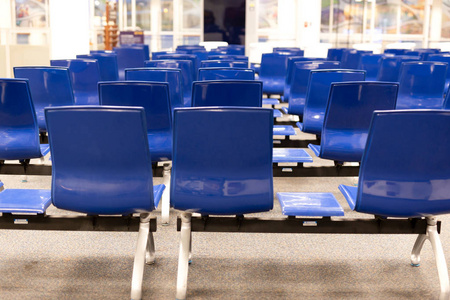 蓝色机场椅子与模糊的人坐和等待离开在机场终端