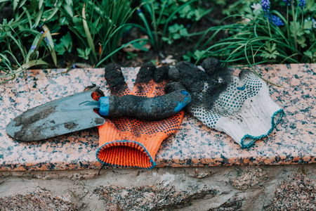 园艺设备。花园的花岗岩板上有不同颜色的工作手套和花园 scoo