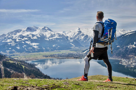 男子站在山顶上的奥地利阿尔卑斯山上, 看着湖和山脉。人手中握着一个罐头