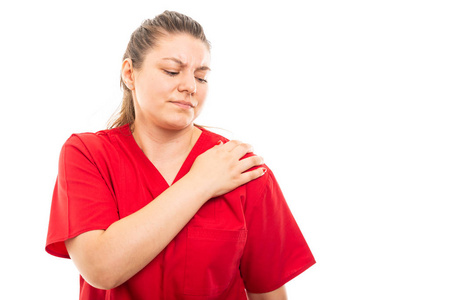 戴红色磨砂的年轻医护护士画像显示 copyspace 广告区白色背景下的肩部疼痛手势