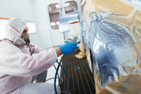 男子用防护衣和面具喷漆车使用喷雾压缩机.选择性聚焦照片