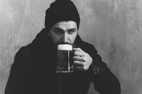 泡沫玻璃在胡子的男人喝啤酒
