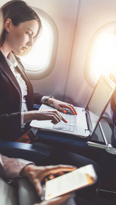 女商人正在她的项目使用笔记本电脑, 而坐在飞机上