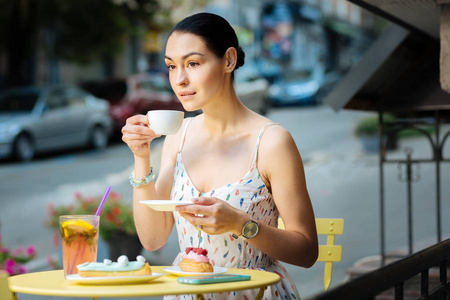 冷静的女人拿着一杯咖啡, 若有所思地喝着它