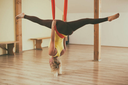 在健身室做空中瑜伽的女人。图像是故意色调
