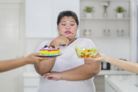 困惑的超重妇女很难选择垃圾食品或健康食品