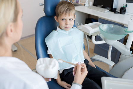 可爱的小男孩的肖像坐在牙科椅和看女牙医解释如何刷牙, 复制空间