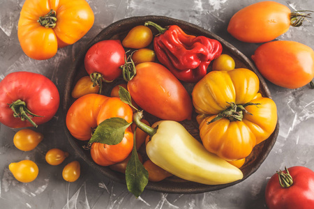 不同类型的西红柿和辣椒在黑暗的背景。清洁饮食概念