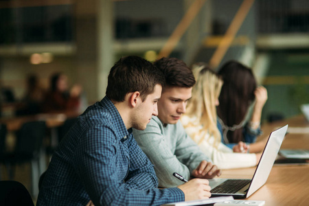 一群在学校图书馆学习的大学生, 一个女孩和一个男孩正在使用一台笔记本电脑并连接到互联网上。