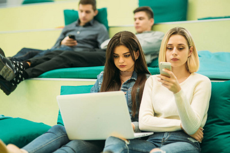 快乐的学生在大学里休息。在使用电话平板电脑和便携式计算机时有一段愉快的时光