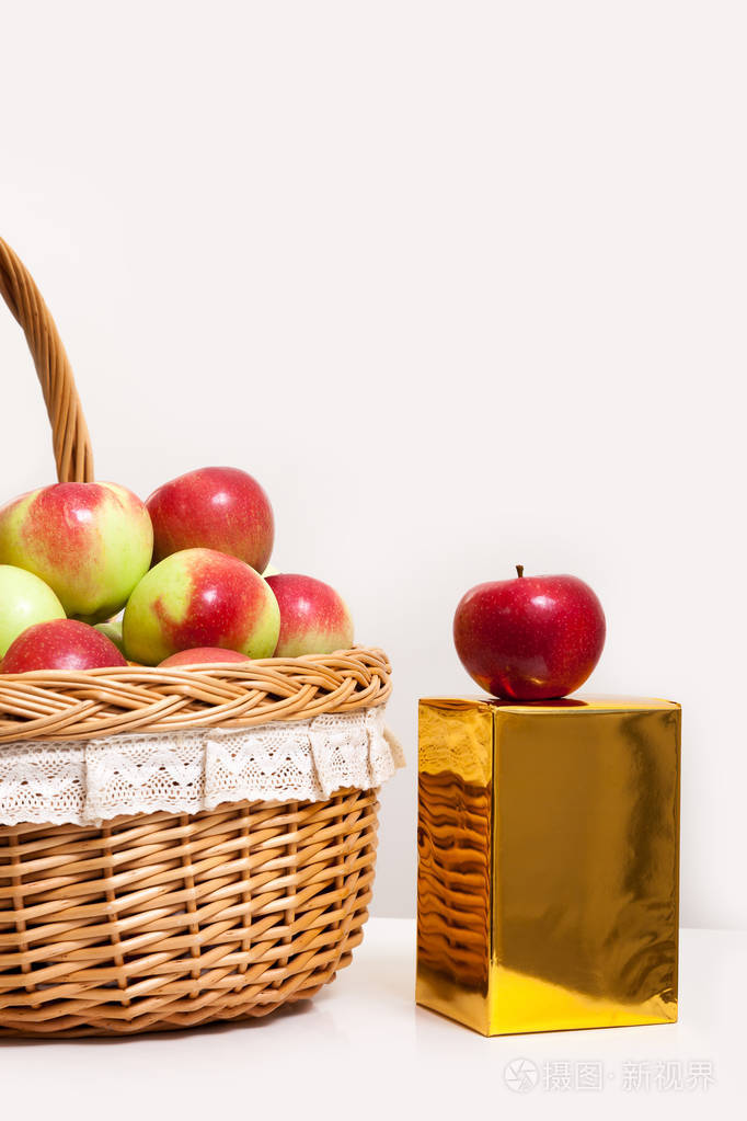 红色和黄色的苹果在一个篮子白色背景.带金礼盒的多汁水果特写