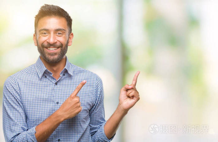 成人西班牙裔男子在孤立的背景下微笑着, 看着相机指着两个手和手指的侧面