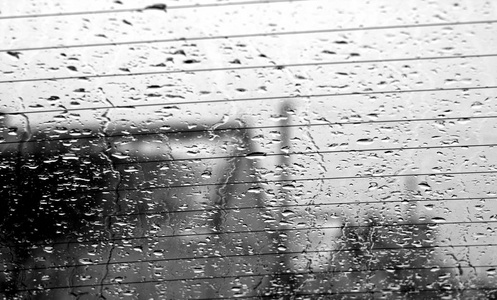 查看通过汽车后窗在雨降与模糊效果。季节性抽象背景