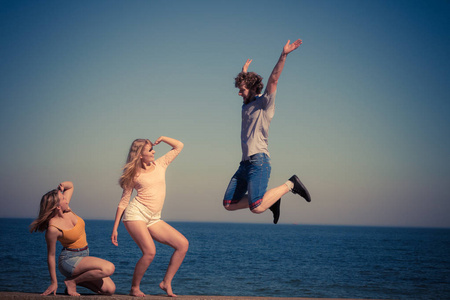 友谊自由夏季假日概念。一群朋友男孩两个女孩花时间在一起的家伙跳的天空