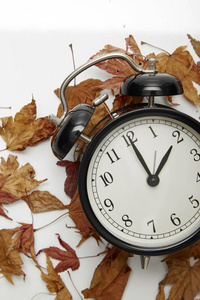 秋季时间的图像变化, 回落概念, 干燥的树叶和老式闹钟在户外的木桌上下午, 为文本