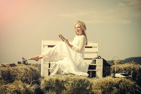 女孩在秸秆花圈和白色连衣裙上阳光灿烂的日子