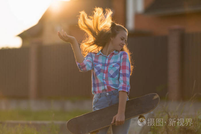 快乐无忧无虑的年轻女子折腾她的头发在空气背光的夕阳橙色的光芒, 她