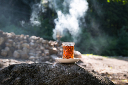 在森林的石头上玻璃上的东方红茶。东方茶的概念。Armudu 传统杯。绿色自然背景。选择性聚焦