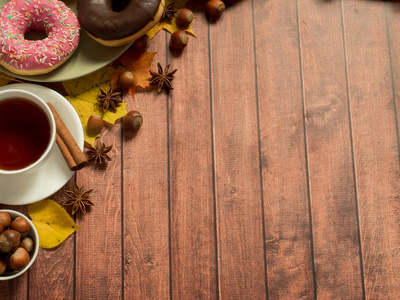 多彩的甜甜圈板秋天和一杯茶，仿古木制背景上的版式。复制空间