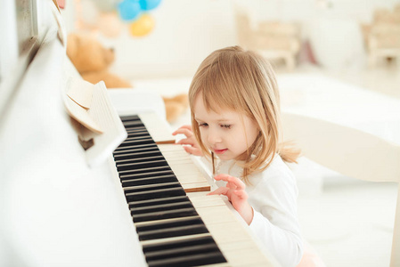 可爱的小女孩，在灯光的房间里弹钢琴