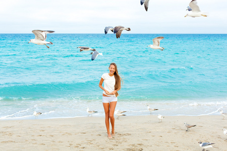 女孩在沙滩上喂海鸥