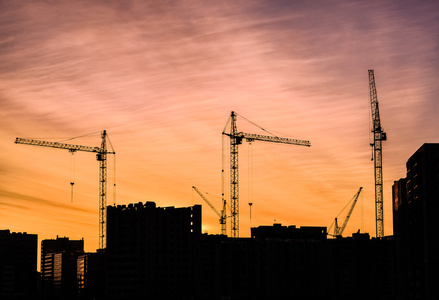 工业建筑起重机和结束日出时太阳大厦剪影照片
