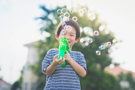 从泡泡在公园里可爱的亚洲儿童射击泡泡照片