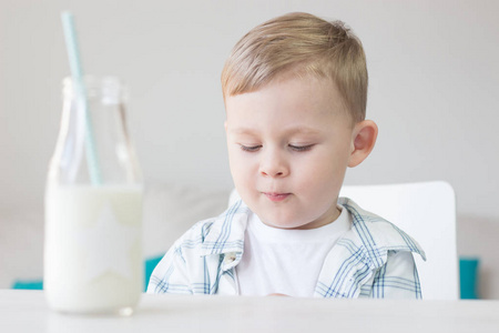 一个可爱的小男孩是吃糖果和喝牛奶。健康。快乐的孩子。早餐。一个小男孩正坐在桌旁