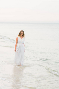 生活方式女人站在海洋海岸垂直镜头上的白色连衣裙