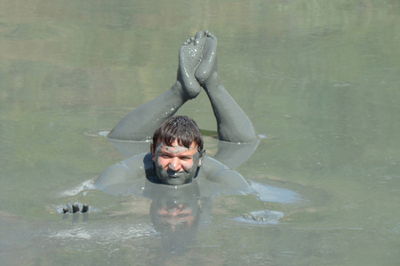 汽车在泥地里一个男孩在泥地里游泳.洗个泥巴澡照片