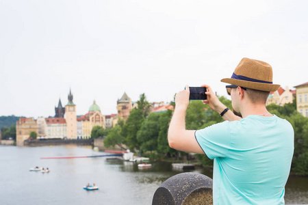 后面的观点，与在河流和城市的智能手机拍照的年轻人旅游