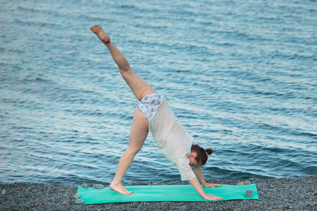 这个女孩被从事瑜伽在海边。在海上练习瑜伽