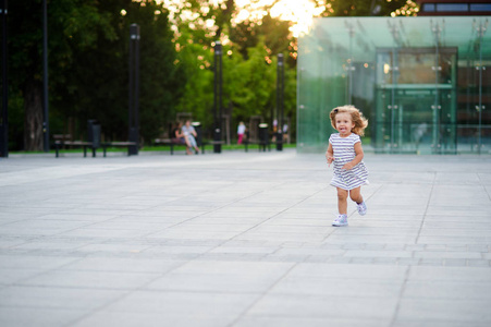 美丽的小女孩在城市公园的广场上奔跑