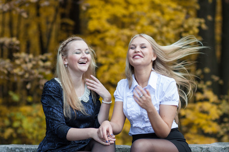 两个年轻女孩谈在片秋色的公园