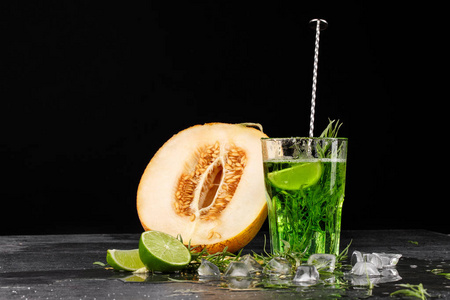 与石灰和龙蒿的绿色饮品。一杯鸡尾酒和黑色背景上的瓜。健康 甜 爽口的饮料。复制空间