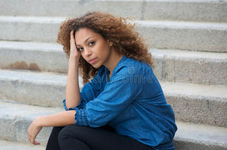 美丽的年轻女人坐在户外的楼梯上