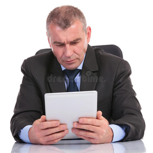 一个商人正聚精会神地看着他的平板电脑