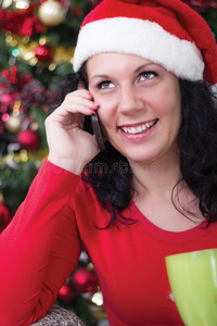圣诞树旁快乐的年轻女子打电话