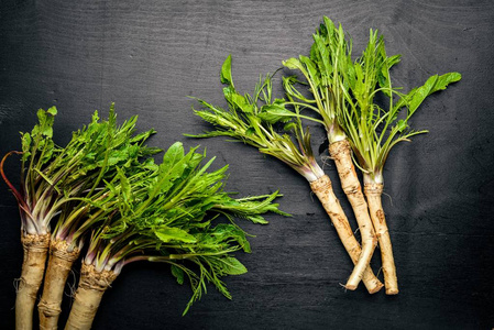 木根新鲜的辣根.在黑色的木桌上.顶视图照片