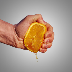 男人的手挤压从橙果汁
