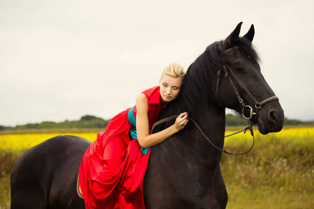 时尚的金发女人,骑着马在阳光明媚的日子.长长的头发照片